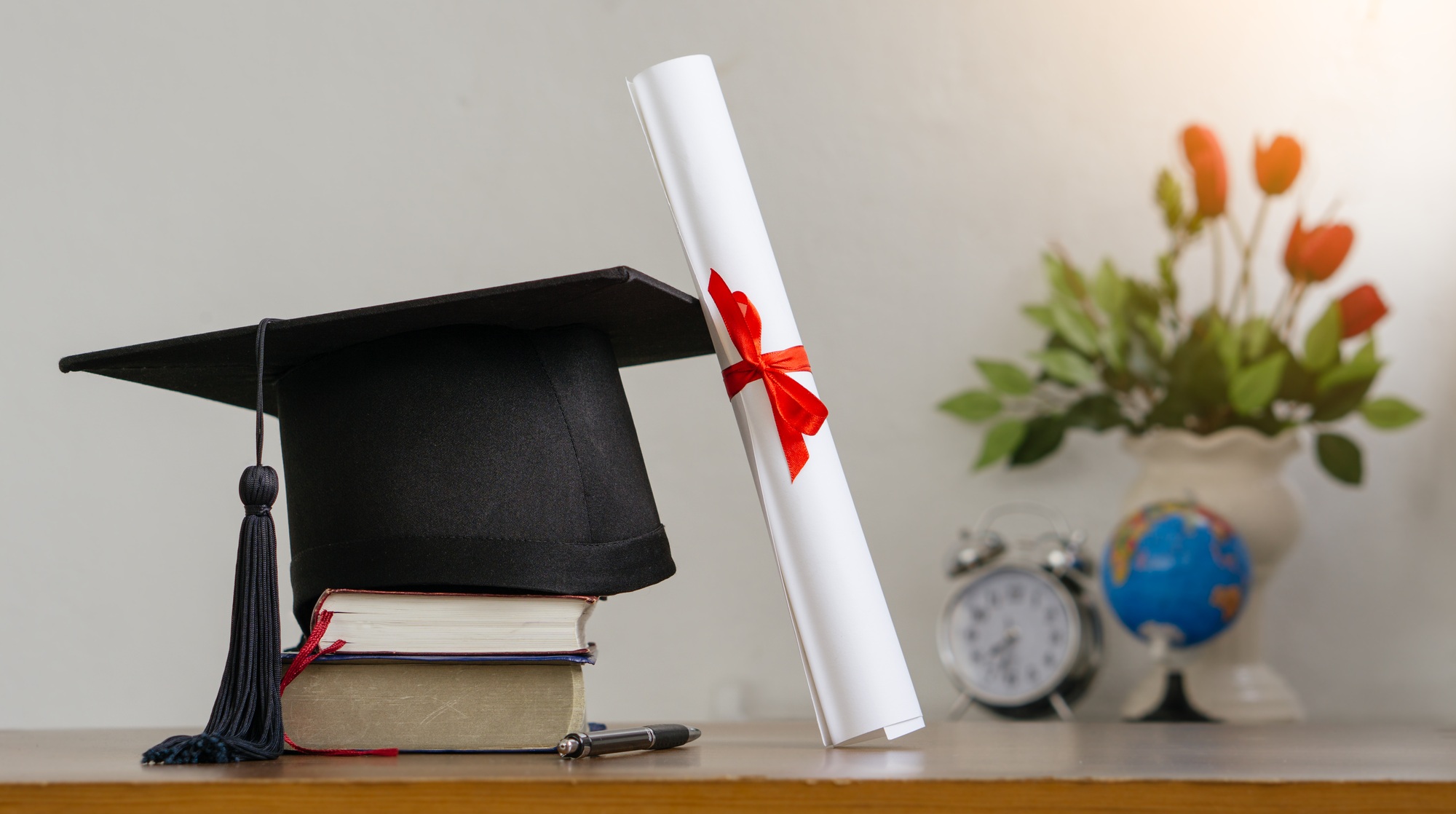 Mortar board with degree paper on wood table. graduation concept.